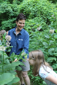 Elsja Fee sniffs some milkweed flowers after Deegan has explained their role in Monarch butterflies' diet and protection from predators.