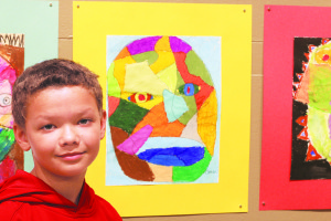 North Side Elementary student Omari Owens stands in front of his work at the Reece Museum. Photo by Jeff Keeling