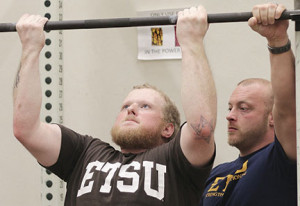 Clemons strains to complete a pull up under the watchful eye of his coach, Derek Wilcox. Photos by Jeff Keeling