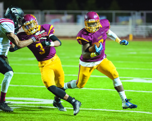 Junior running back King Russell gets to the outside with the help of wide receiver Tyrek Perkins’ block.