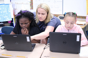 North Side fourth grade teacher Kaytee Dean helps students Korliea Daramie, left, and Aliyah Whitson.