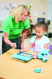 North Side teacher Valerie Orfield discusses a robotics concept with rising third grader Malia Williams as robot “Holly” rests nearby.