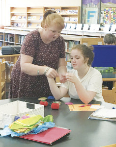 Dr. Johnnie Sue Hawley, left, helps AnnaBelle Walters thread a needle in order to sew a quilt square.