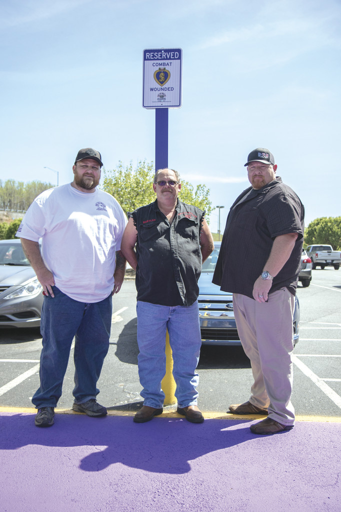 Dog Tag Brigade members Chris Arnold, left, Jeff Hartley and Brad Bowman have been helping to paint different Purple Heart spots across the area. This one is at Lifestyles Fitness Center in Johnson City. Photo by Collin Brooks