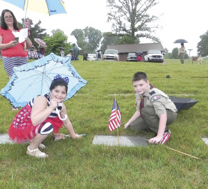 Callie Gillis, left, and Caiden Gillis, Troop 240, place a flag on a relative’s grave. Photos by Bill Derby