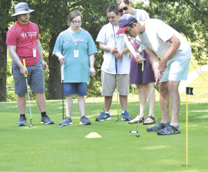 Randy Todd strikes his putt as his team looks on during a competition on the practice putting green.