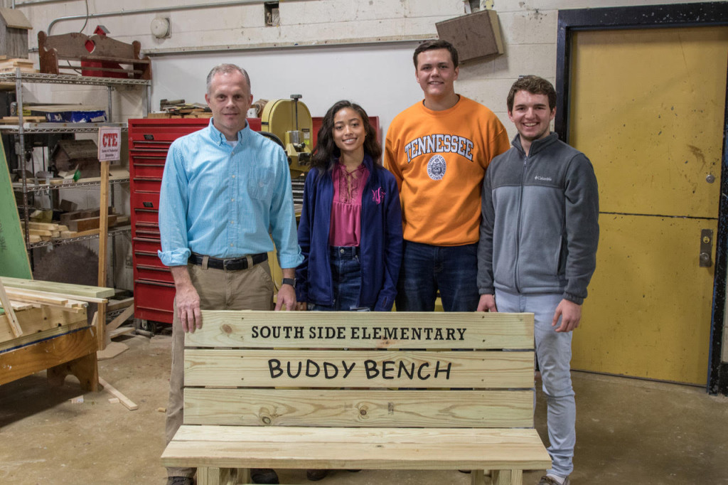 From left to right, construction teacher Robbie Tester, Mariah Anderson, Jackson Bradford and Jedidiah Rope pose behind the finished Buddy Bench. A brain-child of former South Side student Ben Casson, the Buddy Bench is a tool to promote friendship. PHOTO BY COLLIN BROOKS