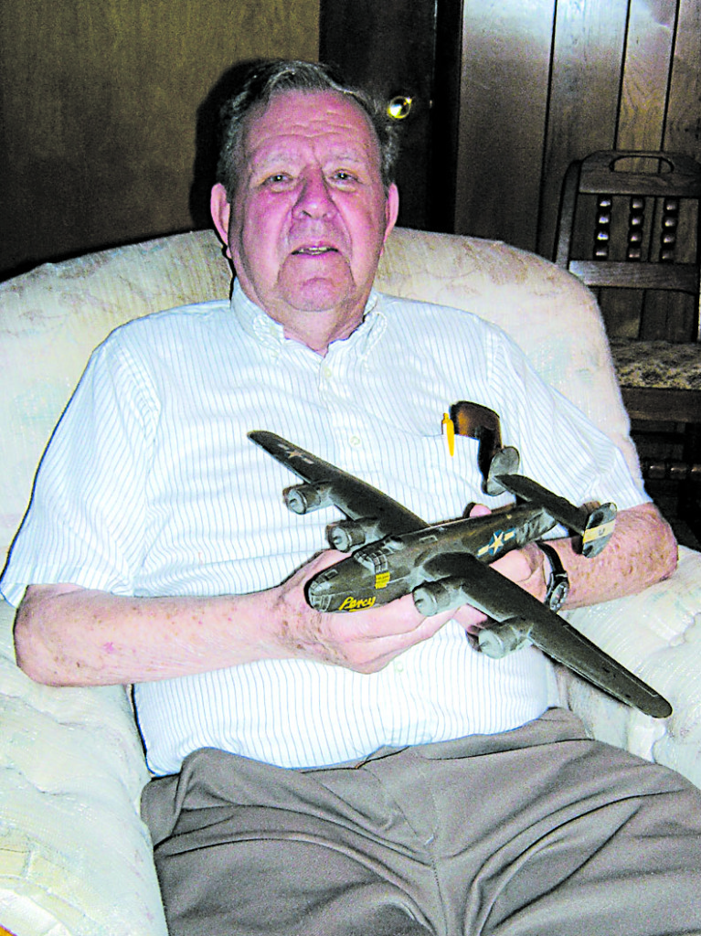 Bill Coleman holds a replica of the B-24 he flew during 30 missions over enemy territory. PHOTO BY BILL DERBY