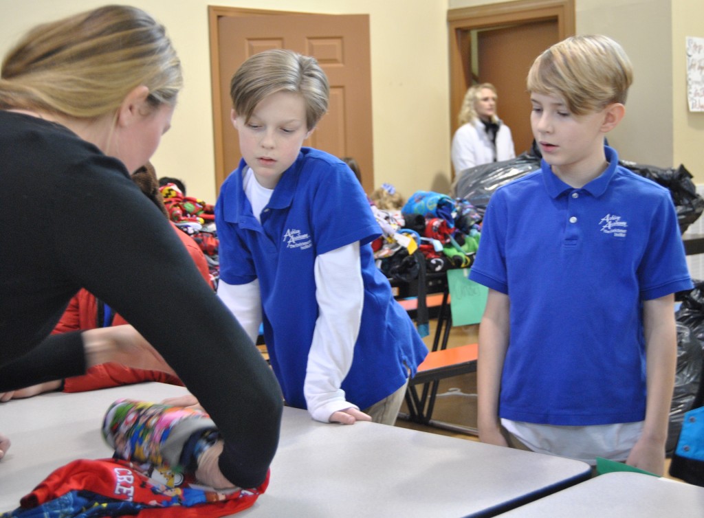 A pair of Ashley Academy students learn how to roll up pajamas, which were collected during a recent charitable initiative by the Kiwanis Club and will be distributed to local children in need. PHOTO BY DAVE ONGIE