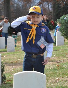Local Cub Scout Braydon Bond salutes after laying a wreath on the grave of a veteran during the annual Wreaths Across America event at Mountain Home National Cemetery on Saturday. PHOTO BY DAVE ONGIE